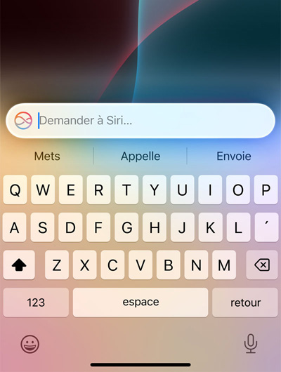 Un clavier sur iPhone surmonté d’un champ de texte où il est écrit, Demander à Siri